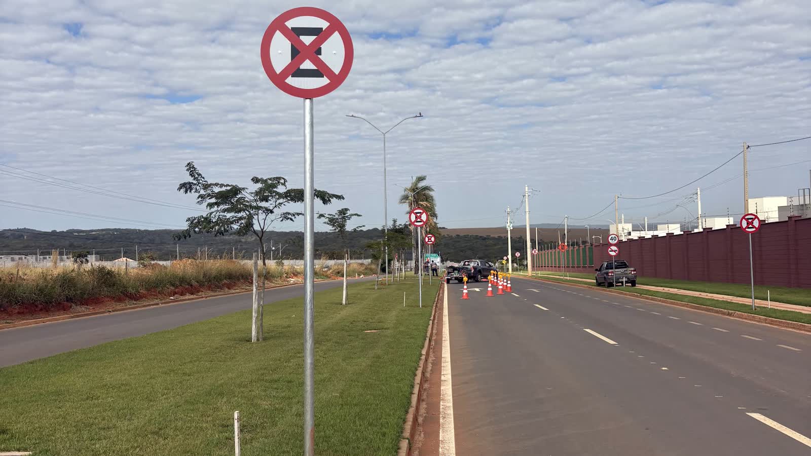 Avenida com canteiro central, faixas pintadas e placas de regulamentação instaladas