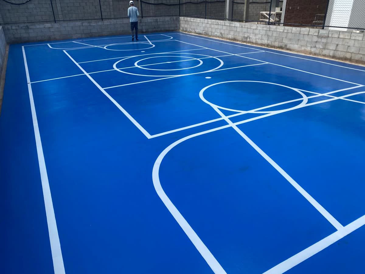 Quadra coberta com piso azul e linhas brancas de basquete e futsal