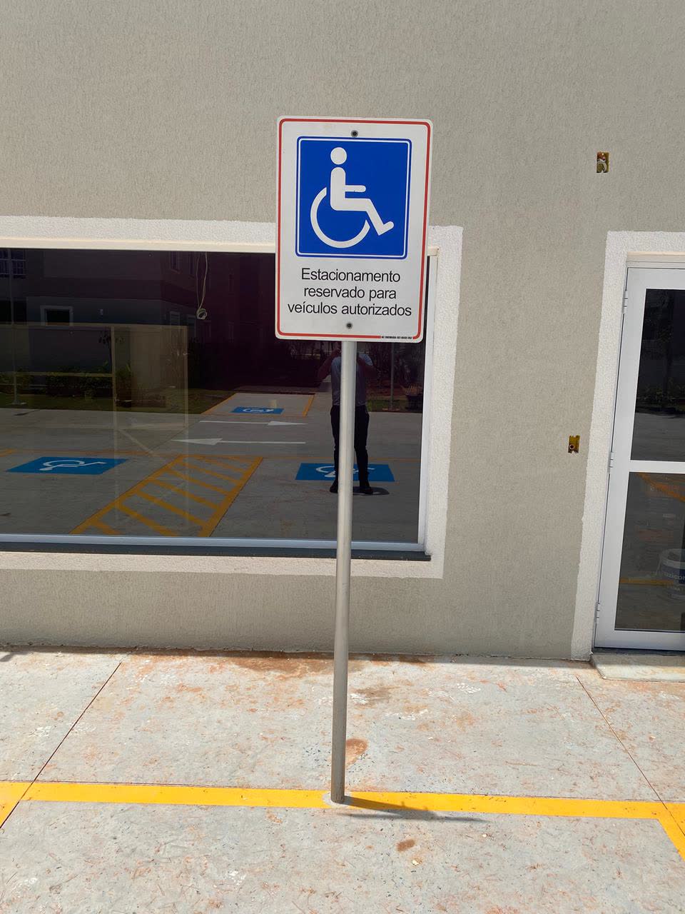 Placa de estacionamento reservado para pessoas com deficiência instalada em frente a edificação