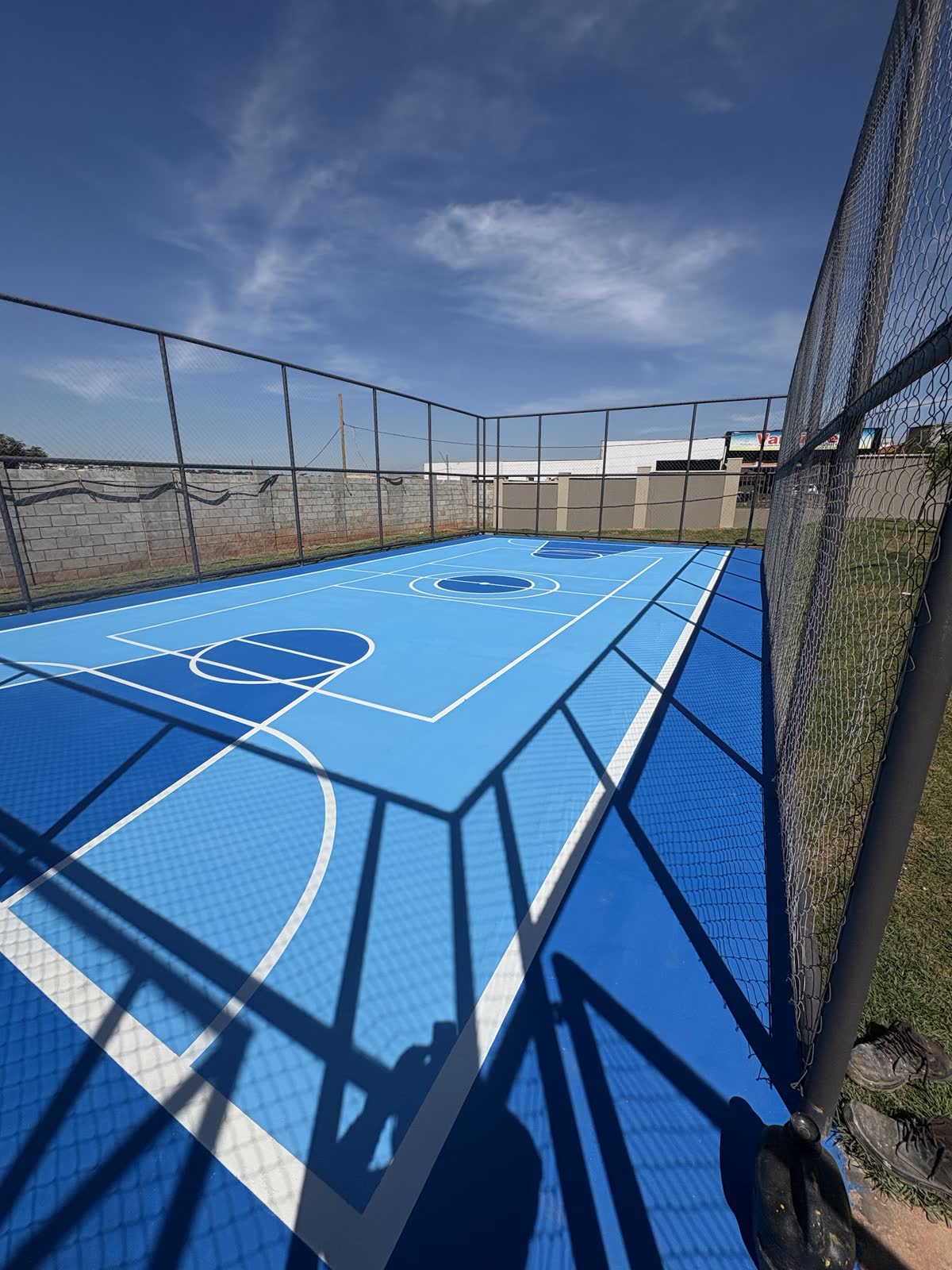 Quadra poliesportiva externa pintada em azul com linhas brancas